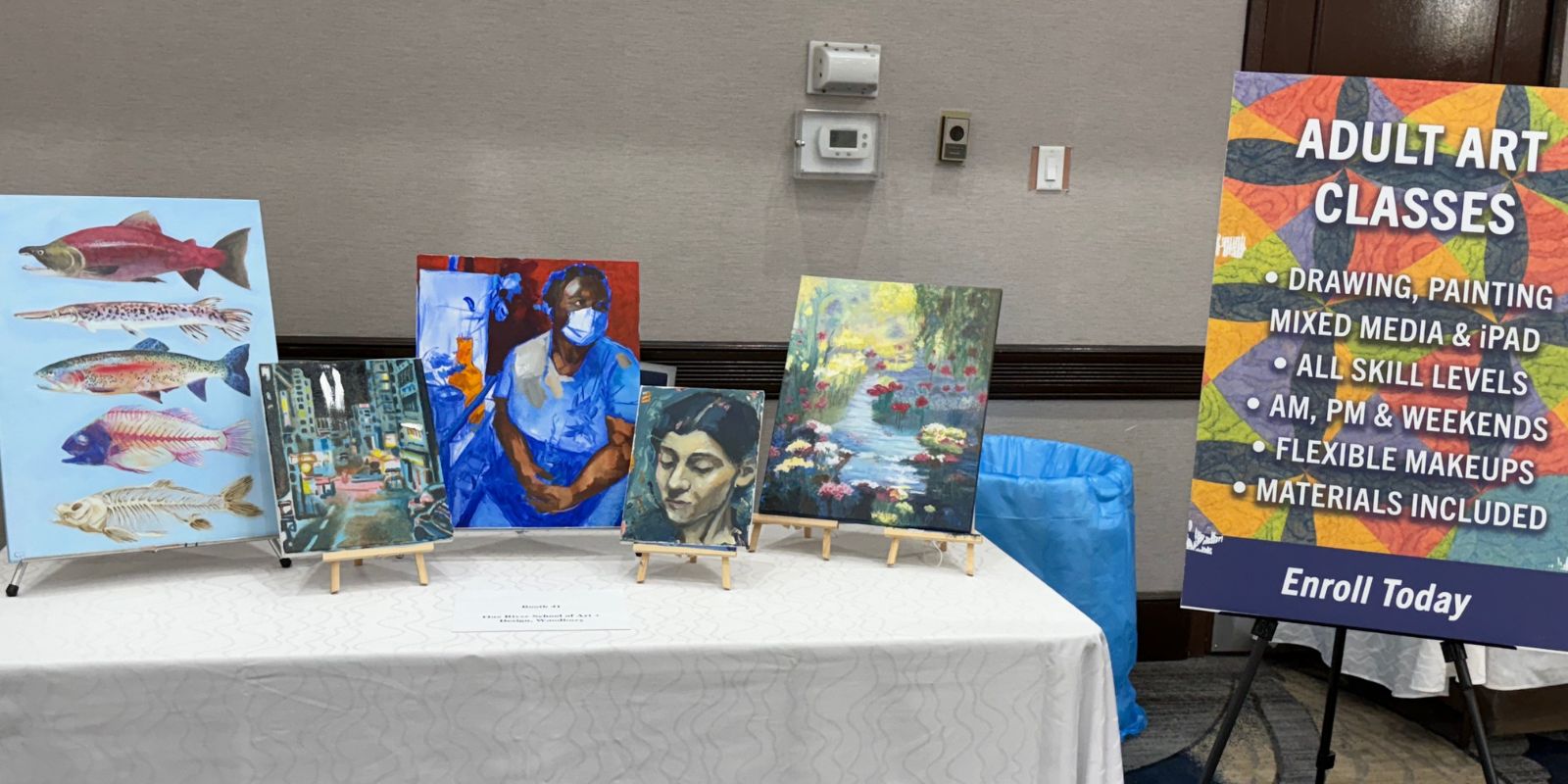 Adult Art Classes booth for One River School featured a sign on a foam board plus some sample pieces of work
