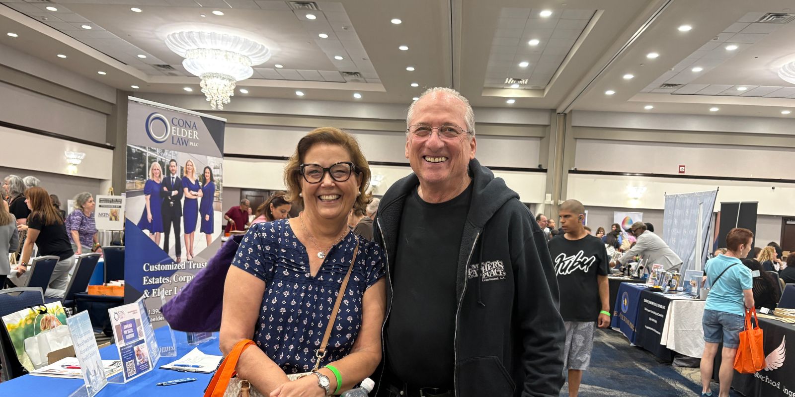 A woman and man smile excitedly… exhibitors in background.