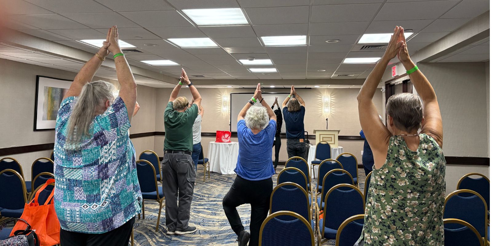 Several students stretch with their arms in an oval above their heads.